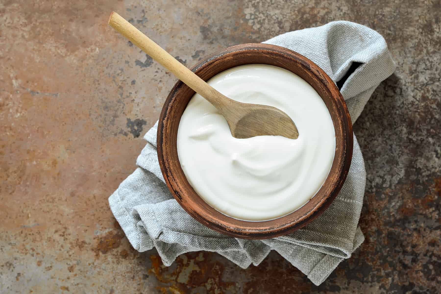 a bowl of sour cream with a wooden spoon in it