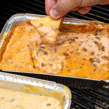 Chip being dipped into a pan of queso