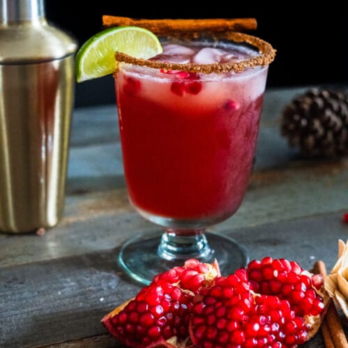 Pomegranate margarita with a cocktail shaker behind it