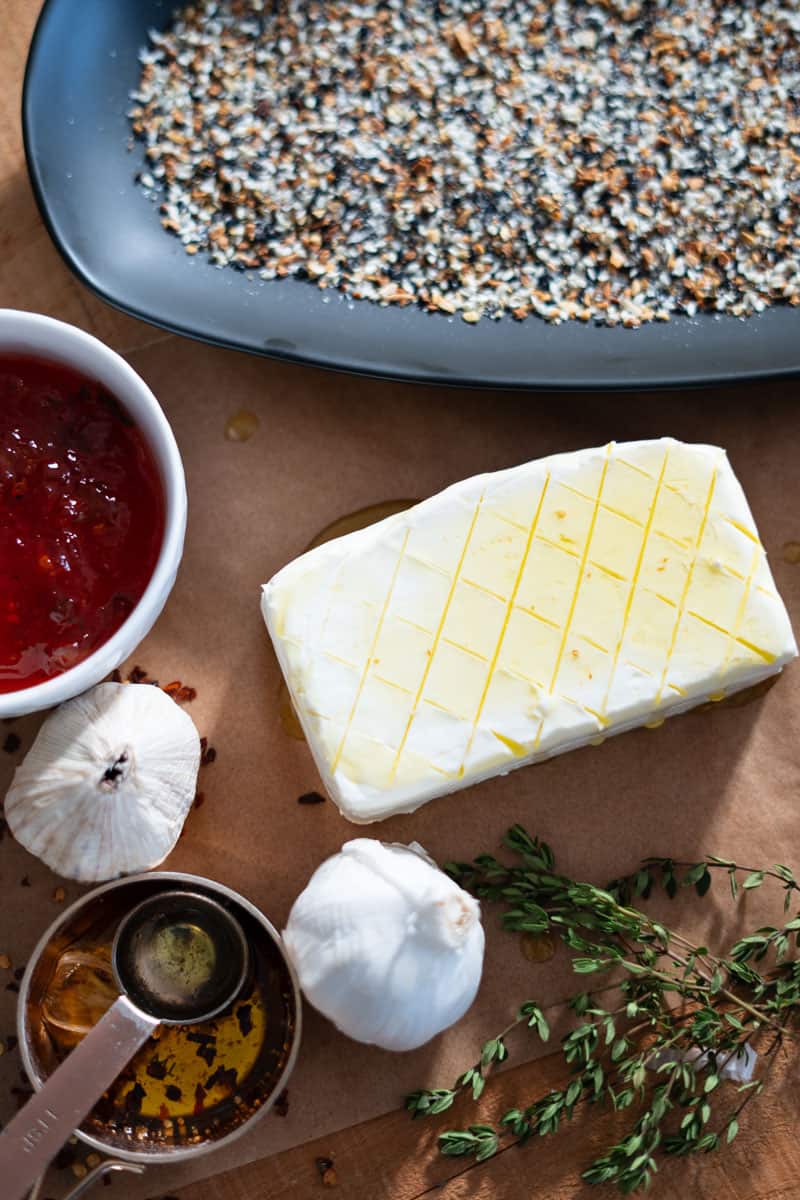 A scored block of cream cheese being brushed lightly with olive oil